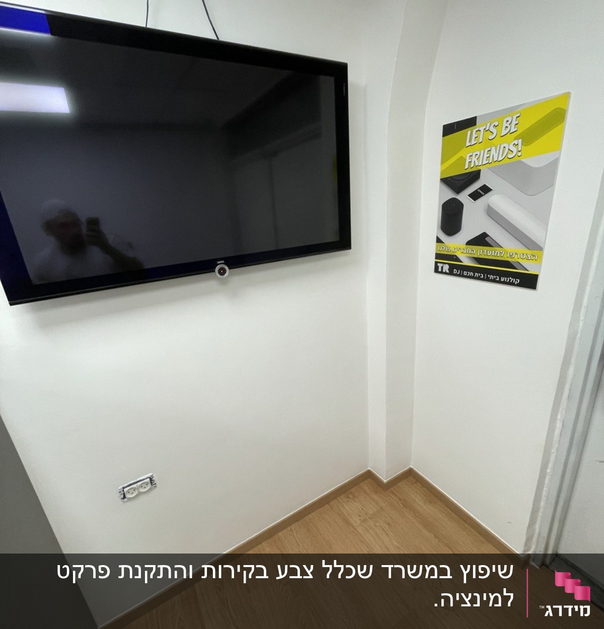 חדר עם טלוויזיה תלויה על הקיר ושקע חשמל